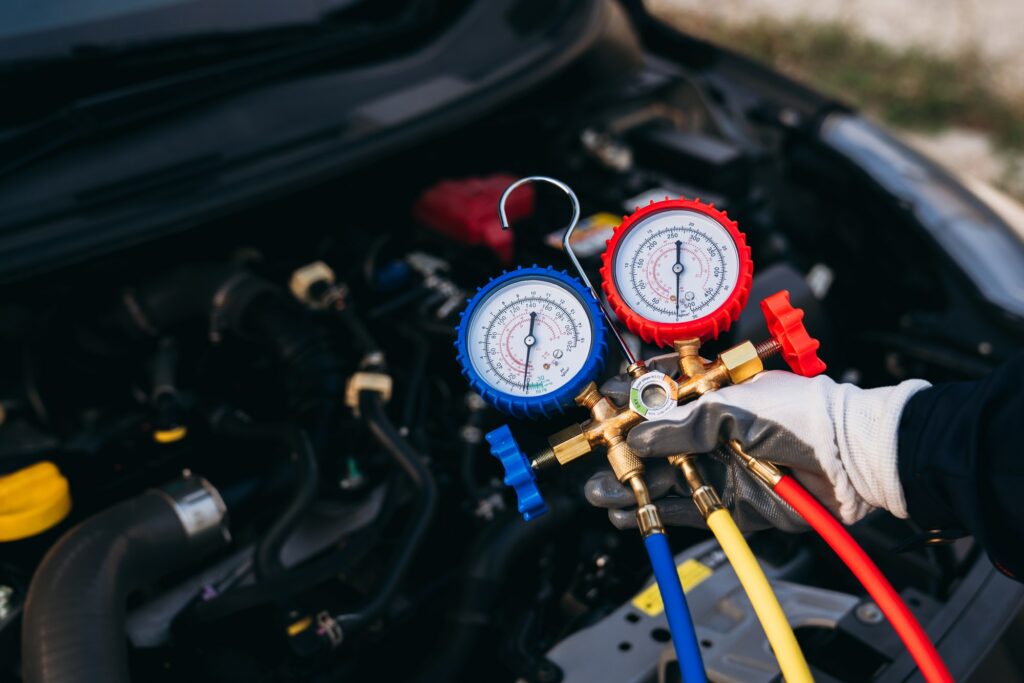 JP Euro technician connecting AC gauges to test refrigerant pressure during a car AC repair in Garland, TX